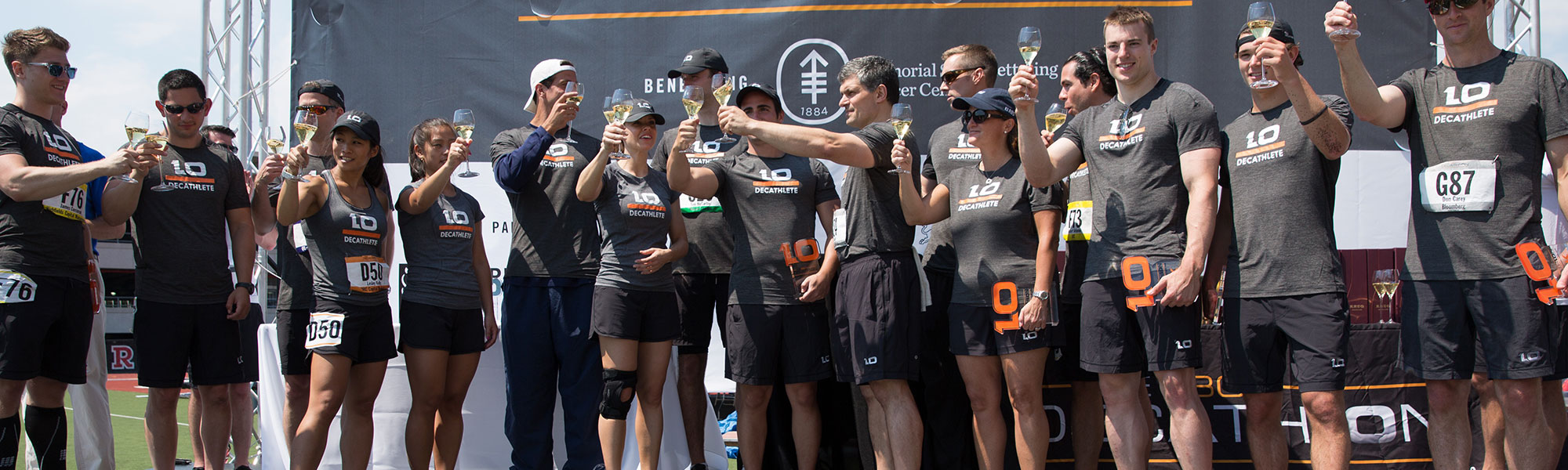 D10 athletes in gray uniforms raise champagne glasses on the track after the 10K Club toast.